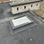 Plat bitumen dak met daglichtsysteem en gemetselde dakrand