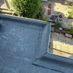 Plat bitumen dak van een aanbouw, gezien vanaf het hoofddak