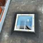 Lichtkoepel ingewerkt in een plat bitumen dak met loodslabbe